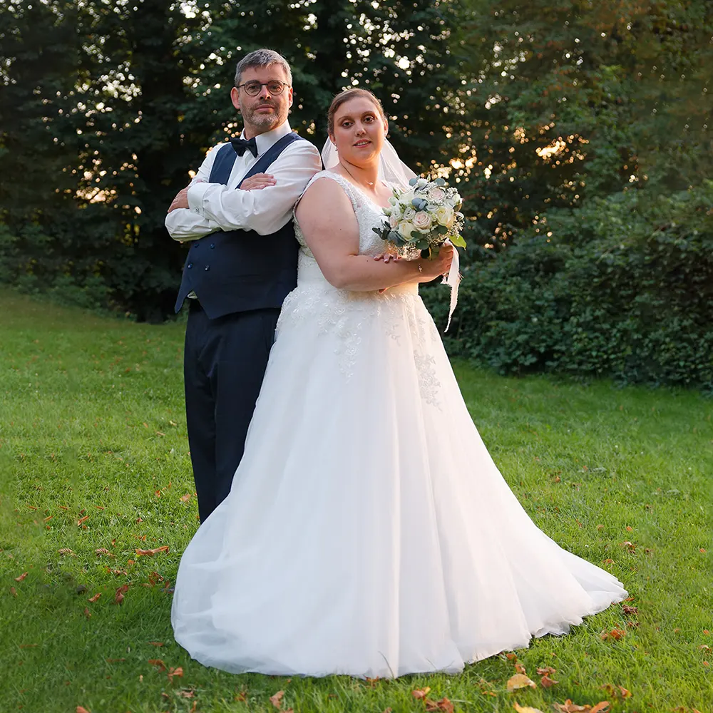 Photo de couple de mariés dos à dos | Photographe Arras Photographie de couple de mariés posant de dos à dos dans un parc, au soleil couchant. Une pose originale et pleine de force capturée par un photographe de mariage au Mont Saint Eloi..