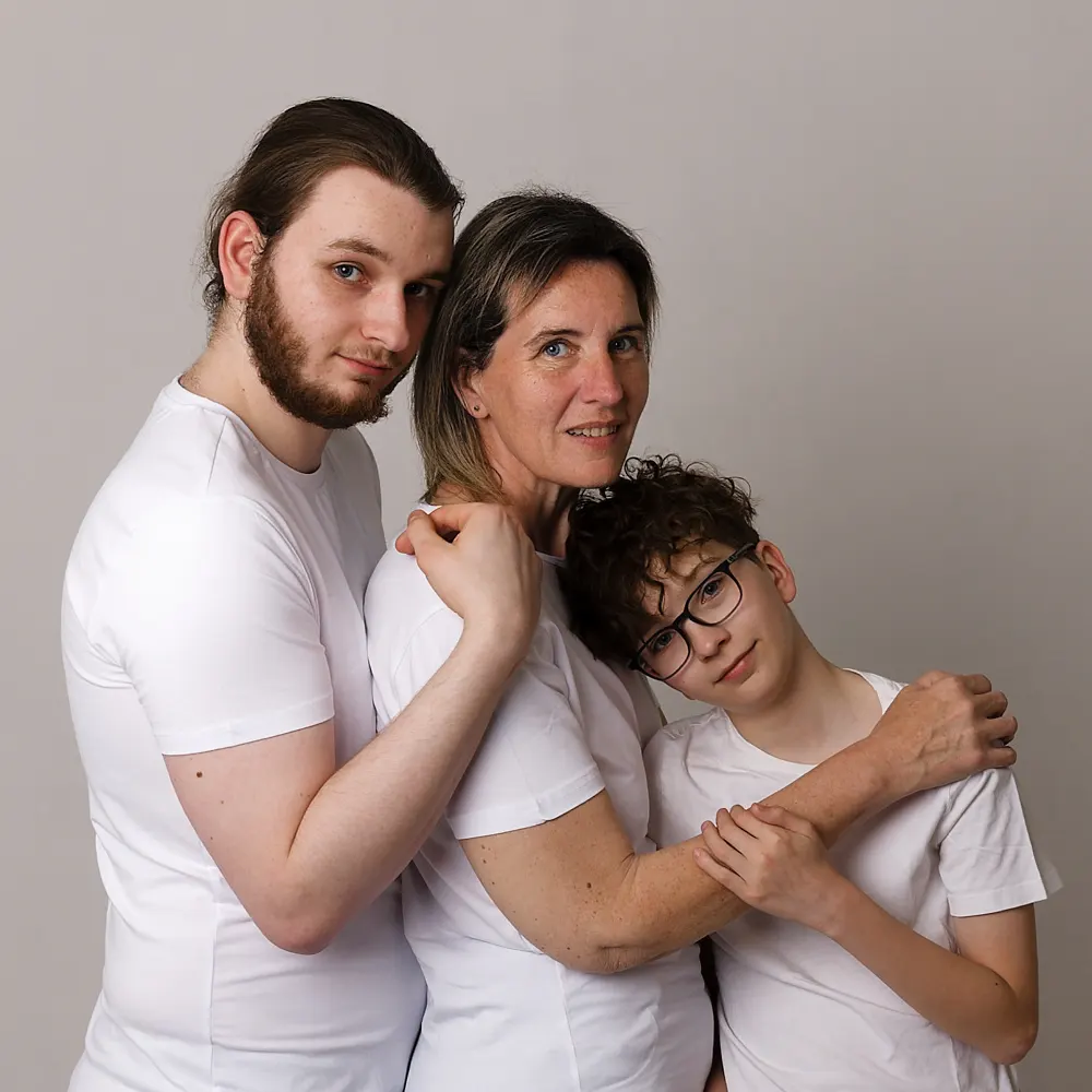 Portrait de famille en studio d'une mère et de ses deux fils, posant côte à côte avec une expression de complicité, réalisé par un photographe de Sainte-Catherine.