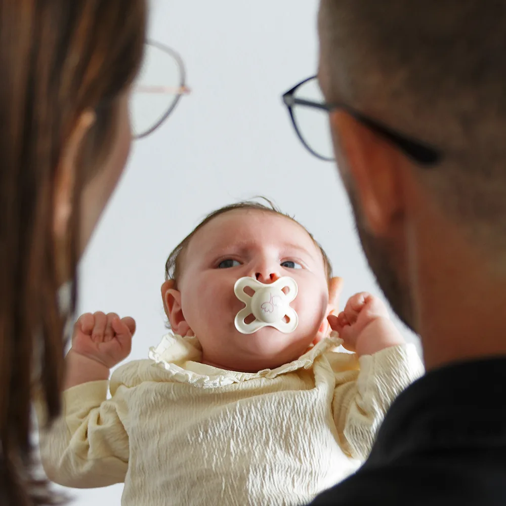 Shooting d'un bébé sur arras. Le bébé est au centre de la photo, et ses parents sur l'extérieur sont de dos, et flou par la profondeur de champ. Ils regardent leur enfant