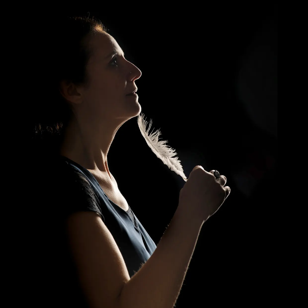 Portrait en studio, jeu d'ombre et de lumière sur un visage, une plume en main, à Arras.