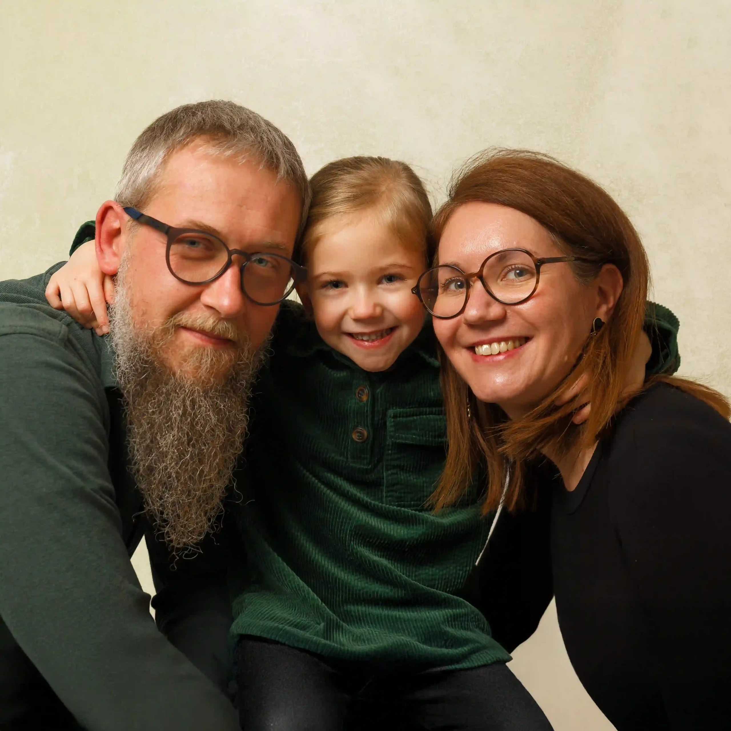 Gros plan sur une famille heureuse, le père, la mère et la fille s'enlacent et sourient ensemble, capturant un moment de joie par un photographe de Sainte-Catherine.
