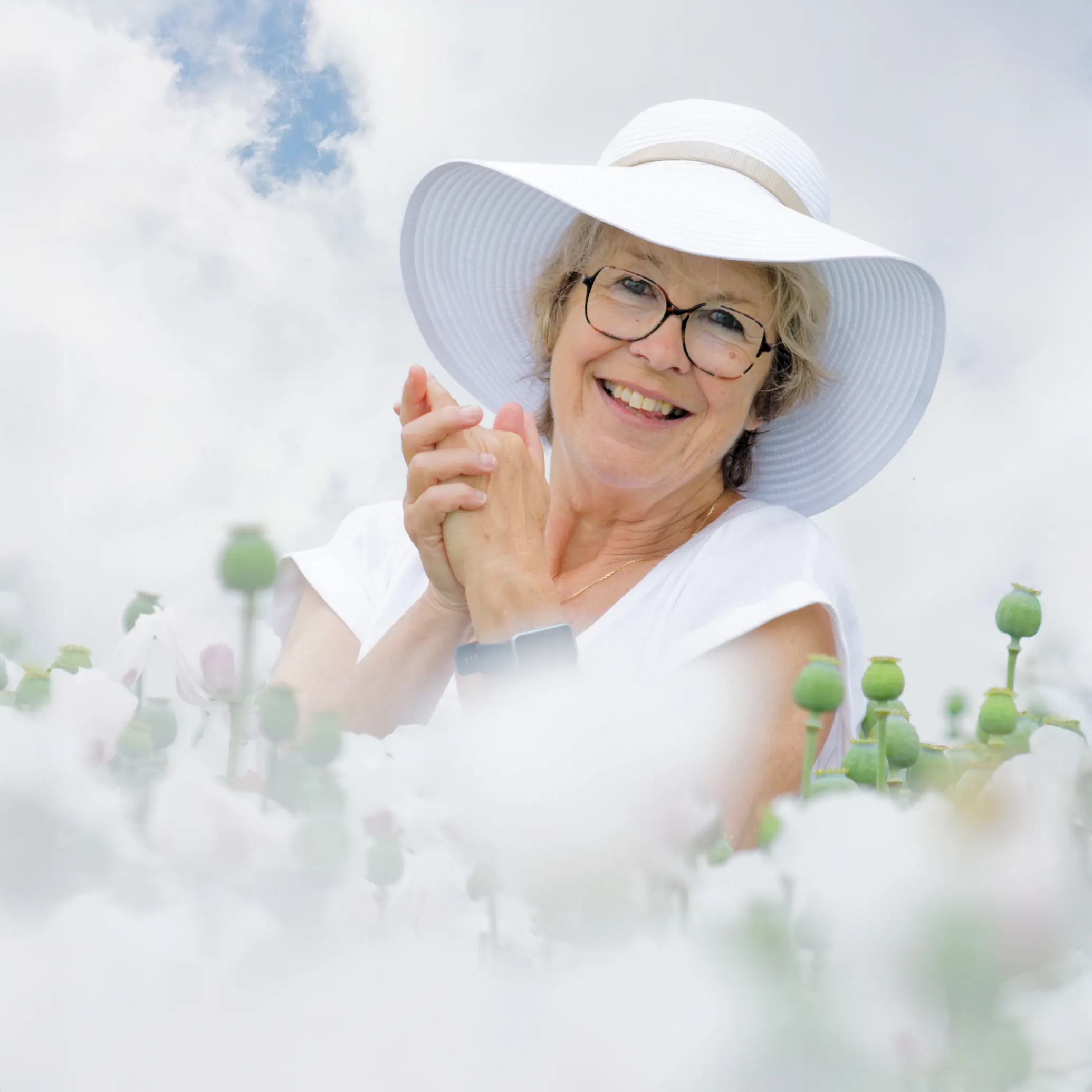 Portrait de femme souriante au milieu de pavots blancs, séance photo en extérieur par un photographe à Sainte-Catherine près d'Arras.