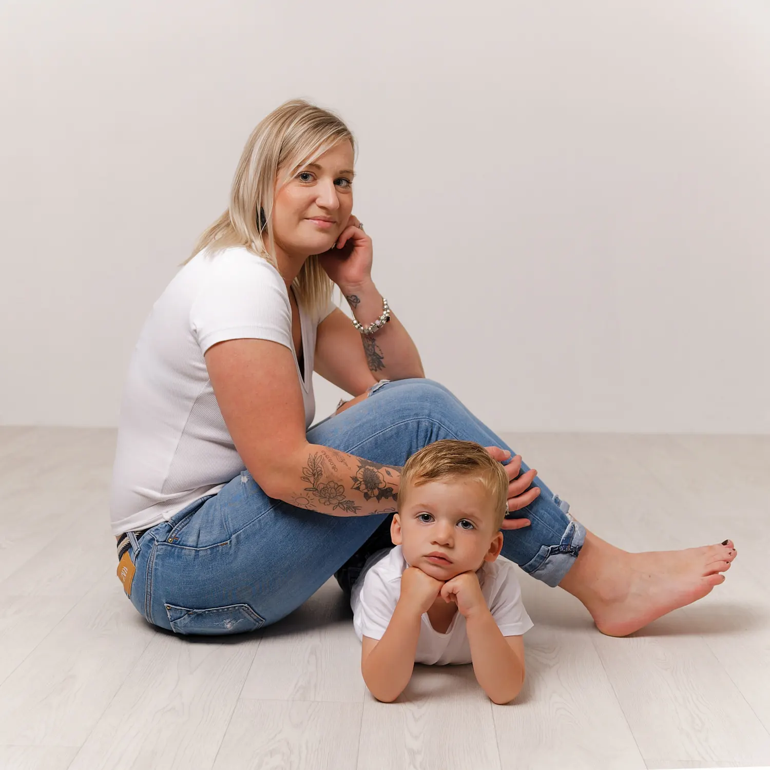 Portrait de famille en studio d'une mère et de son fils allongés sur le ventre, tous deux face à la caméra, un moment de complicité capturé à Sainte-Catherine.