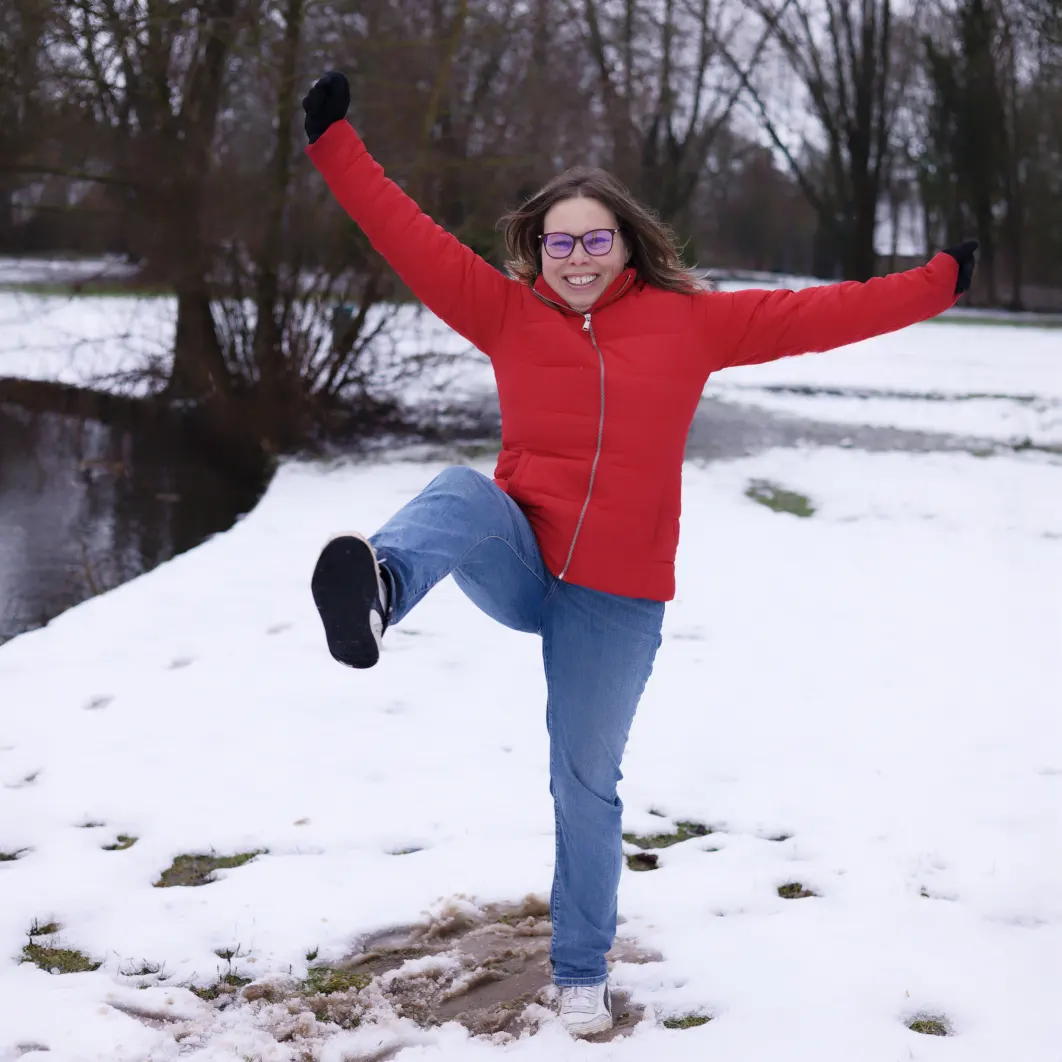 Portrait de femme joyeuse en doudoune rouge dans la neige, photo d'hiver en extérieur réalisée à Arras