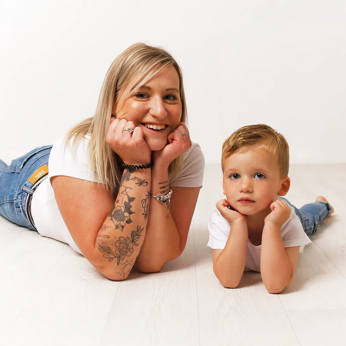 Photo en studio d'une mère assise sur le sol, regardant la caméra, avec son jeune fils allongé devant elle, une pose décontractée capturée par un photographe à Sainte-Catherine, à côté d'Arras.