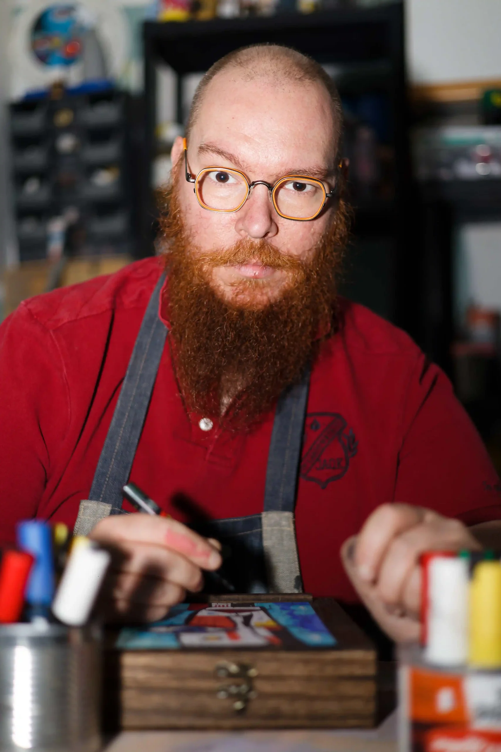 Portrait en gros plan d'un artiste en train de peindre un objet en bois dans son atelier avec un stylo-feutre.