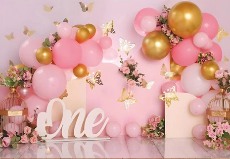 Fond photo représentant une scéne pour un anniversaire d'une petite fille d'un an. Il y a des ballons roses et dorés en arche, agrémenté de papillons.