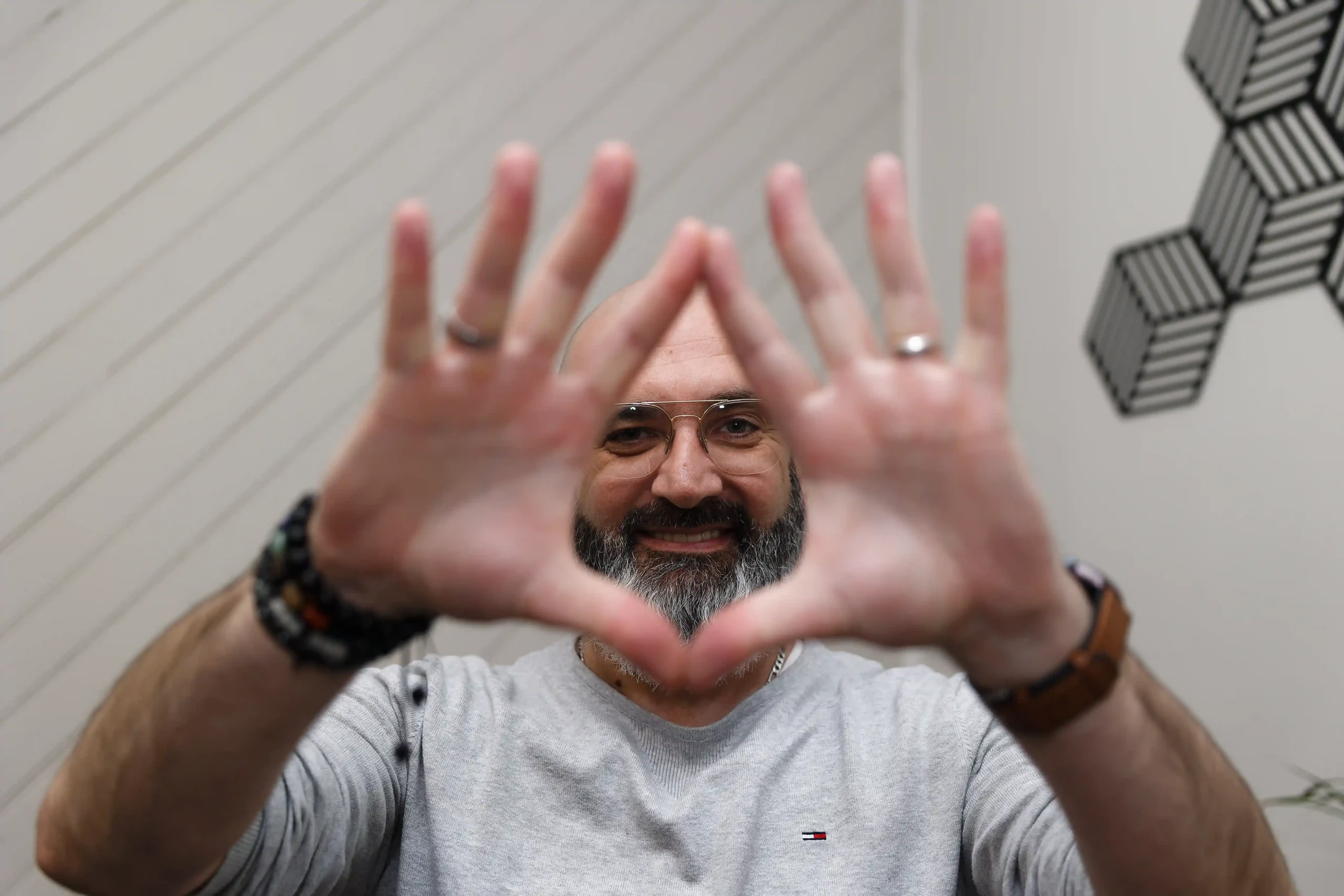 Portrait d'un hypnotiseur souriant, regardant à travers ses mains, symbolisant une séance d'hypnose ou de visualisation.