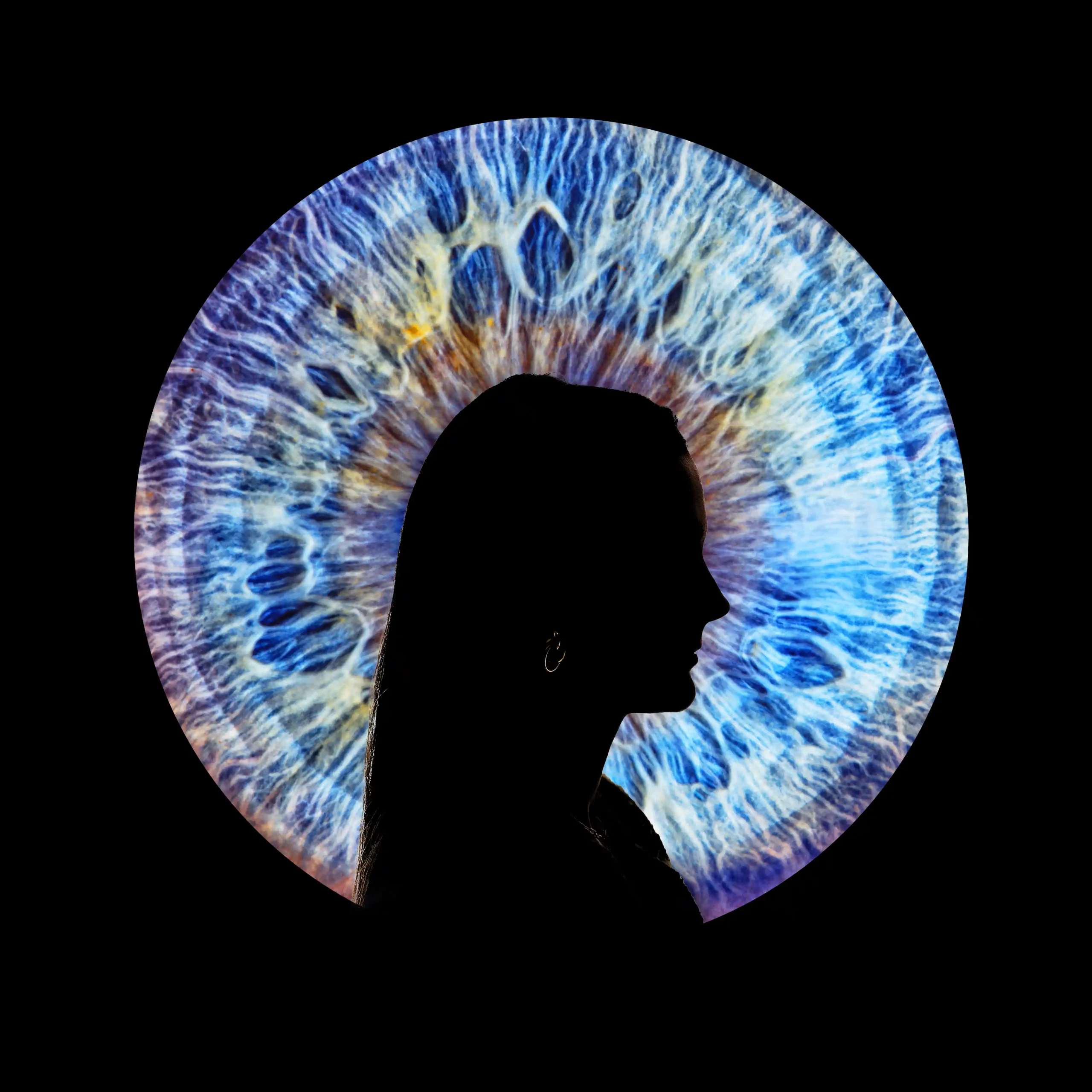 Portrait artistique d'une silhouette féminine vue de profil, superposée sur un très grand plan macro d'un iris bleu et jaune lumineux. Le fond est noir.