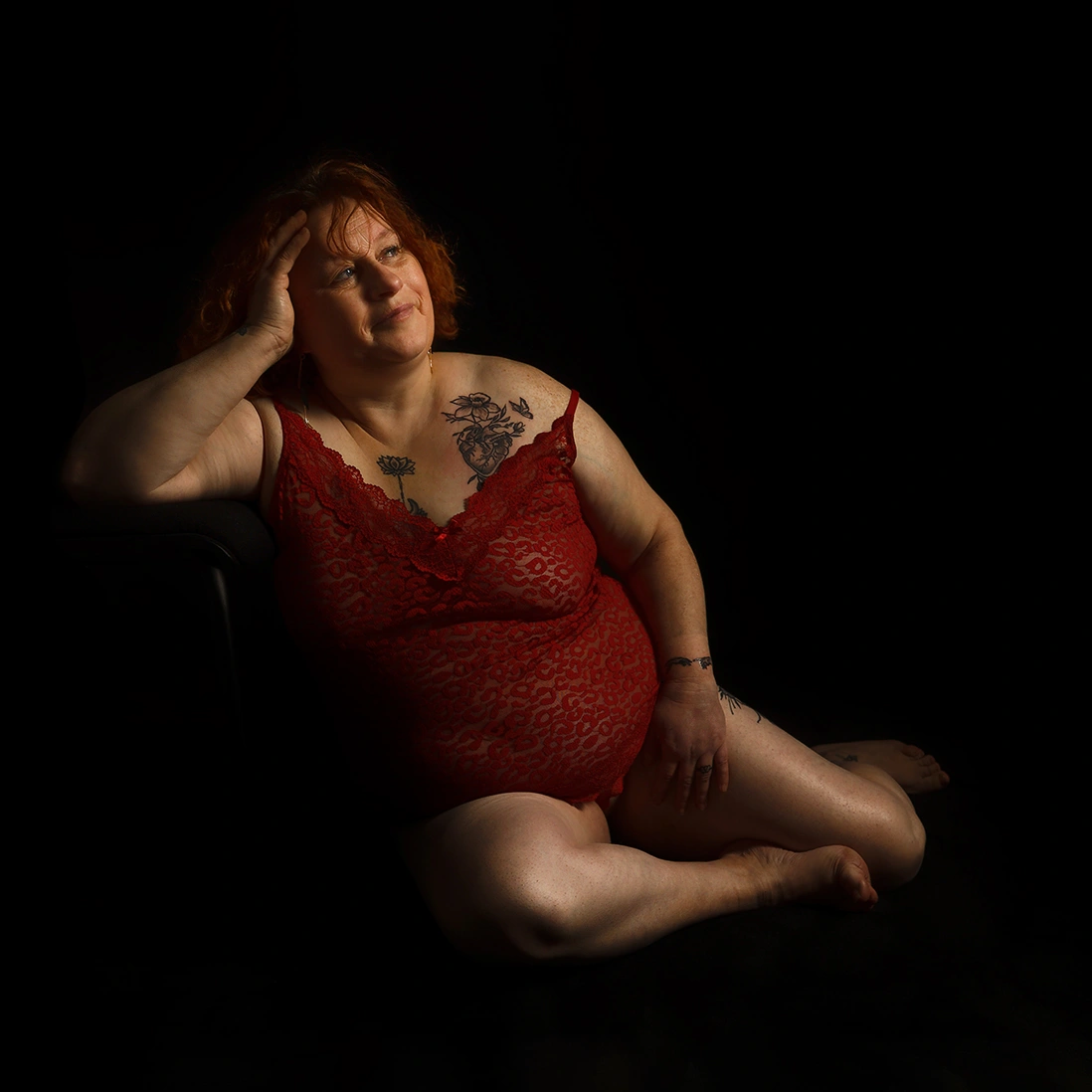 Femme en lingerie rouge posant de façon détendue. Séance de photographie boudoir intime à Sainte-Catherine, par un photographe spécialisé.