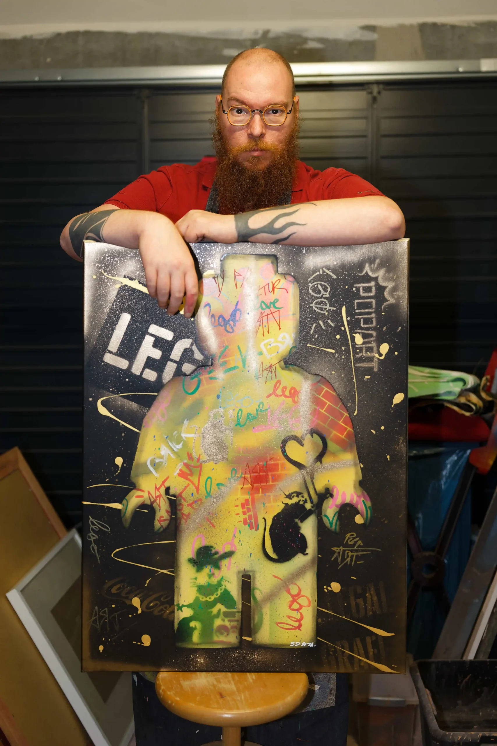 ·	Portrait d'un artiste barbu avec un tablier de travail, posant fièrement avec son tableau de style urbain.