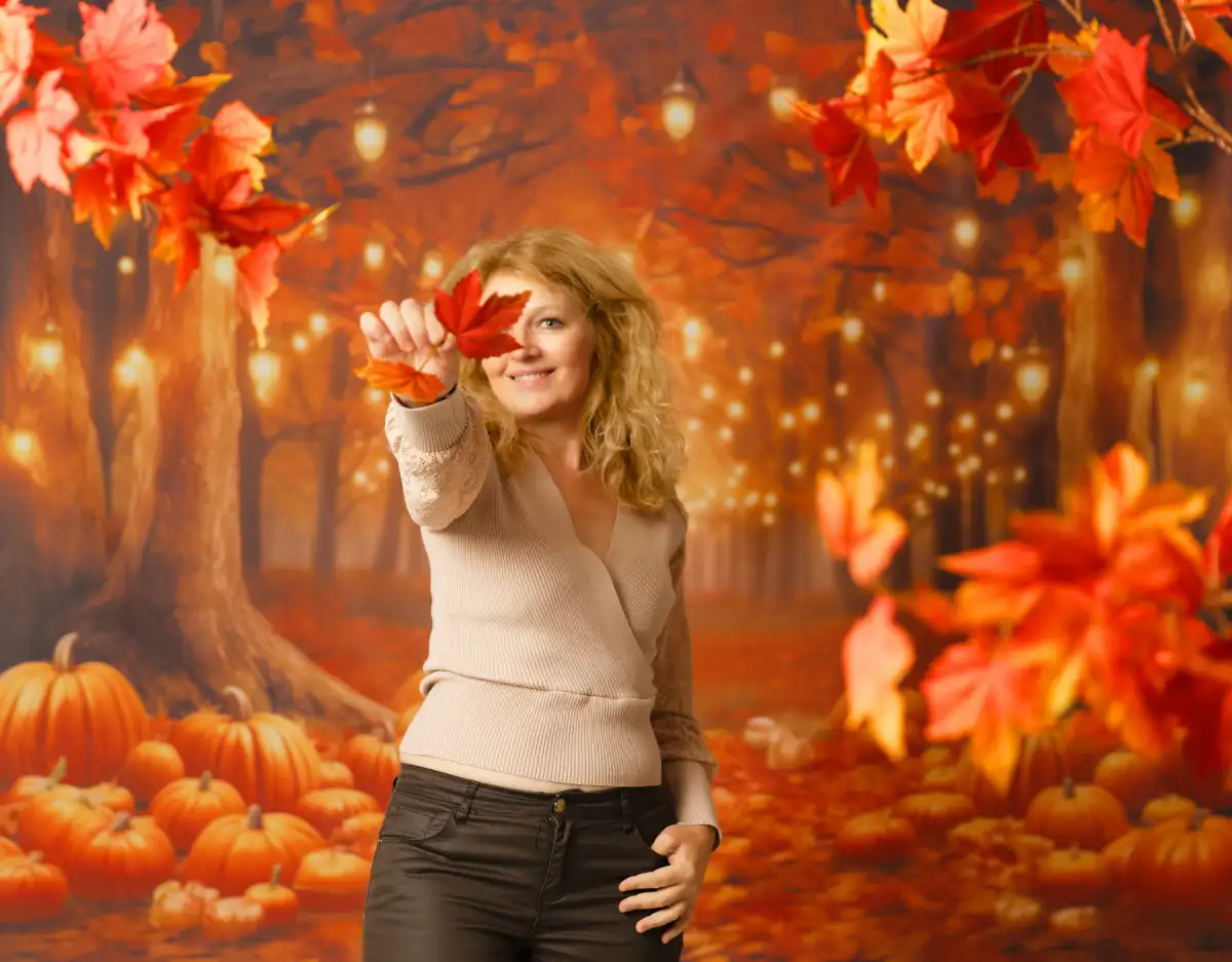 Portrait d'une femme devant une fond de studio. Ce fond photo représente un décor d'arbres, de lumière, et de citrouilles, dans les couleurs d'automne
