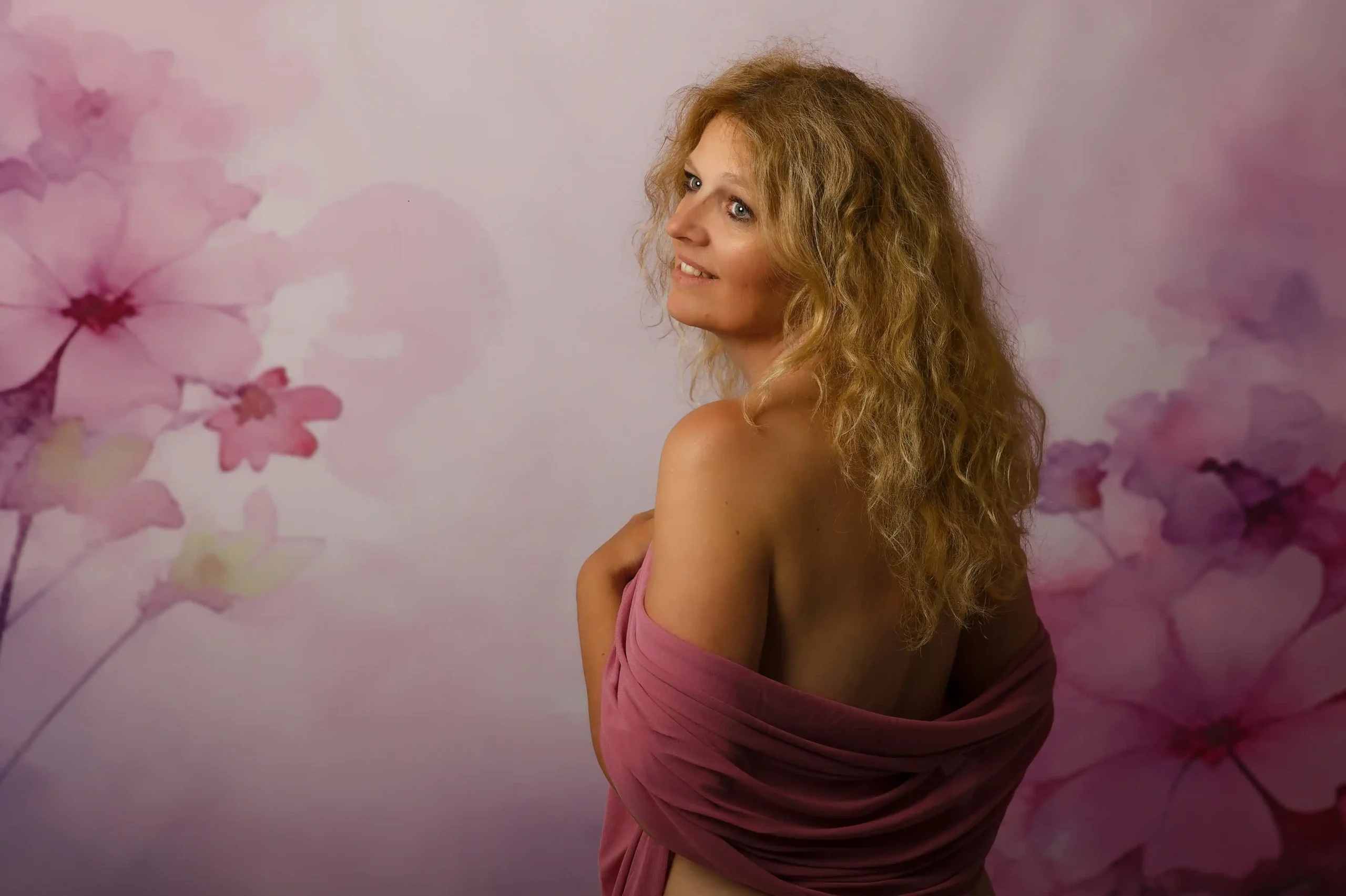 Portrait devant une toile de fond studio. Ce fond représente des fleurs fondues de couleur rose.