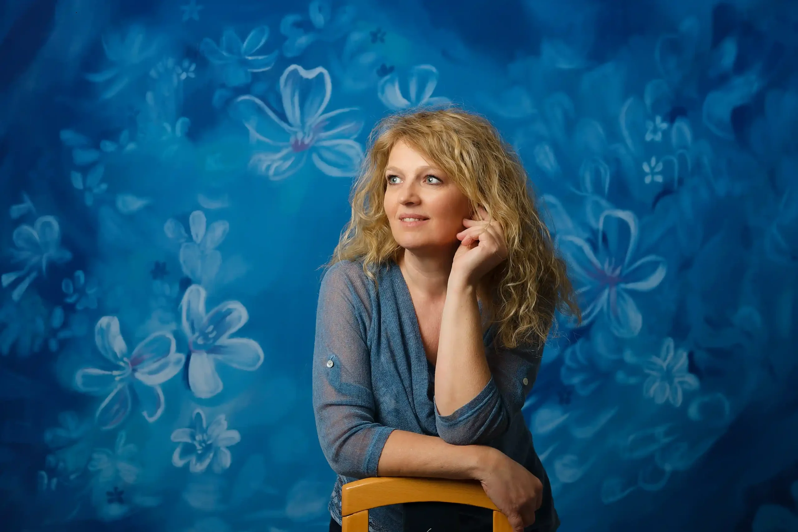Portrait devant un fond studio. Cette toile de fond représente un fondu de fleurs bleues.