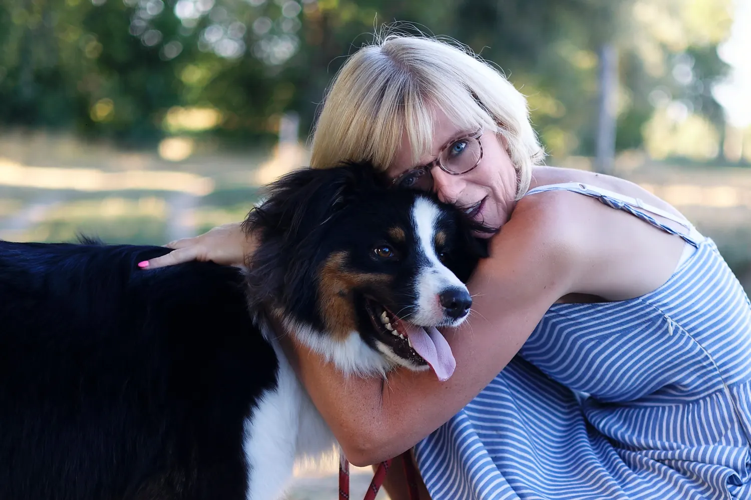 shooting d'un chien avec sa maitresse. La femme prend son chien à grand bras et lui fait un calin.