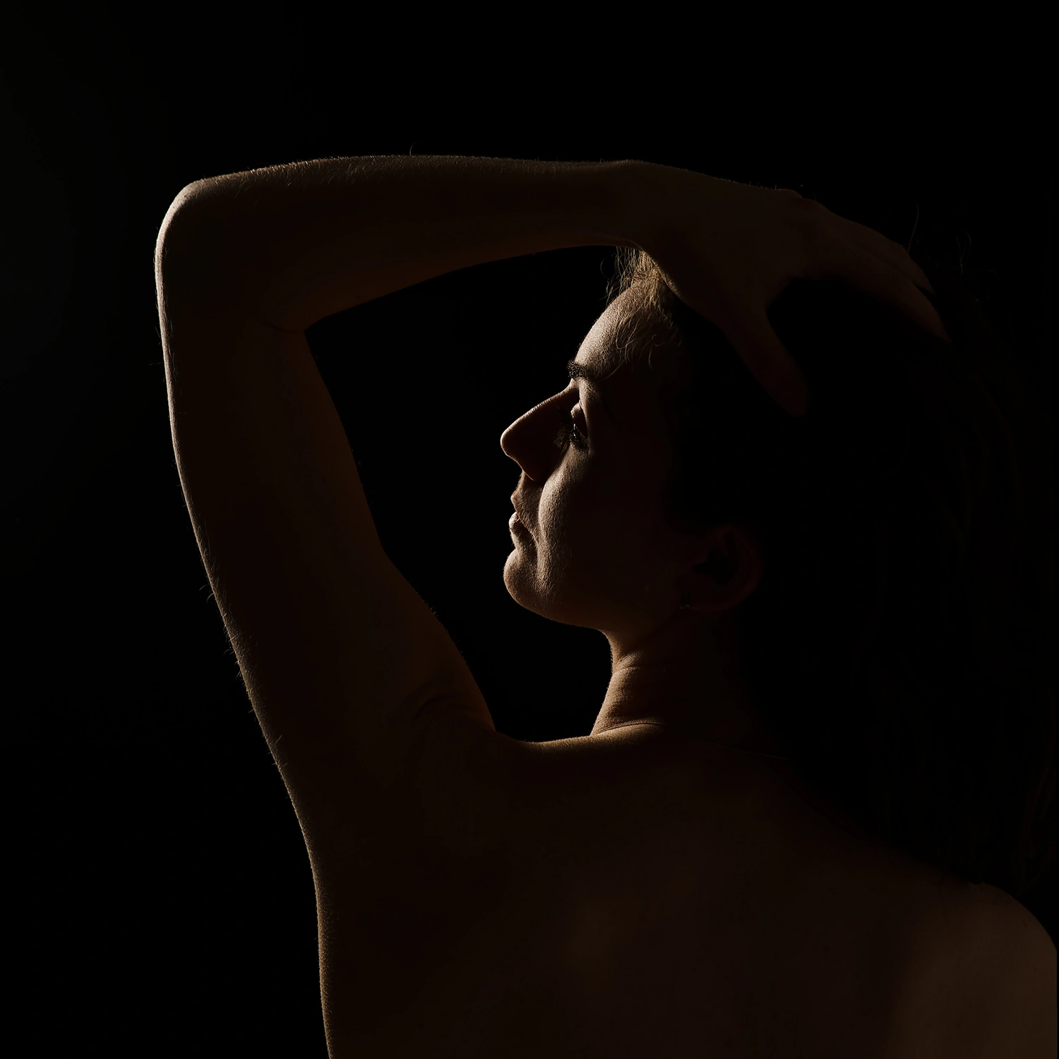 Gros plan d'une silhouette de femme avec un jeu de lumière sur son bras. Photographie de boudoir créative près d'Arras.