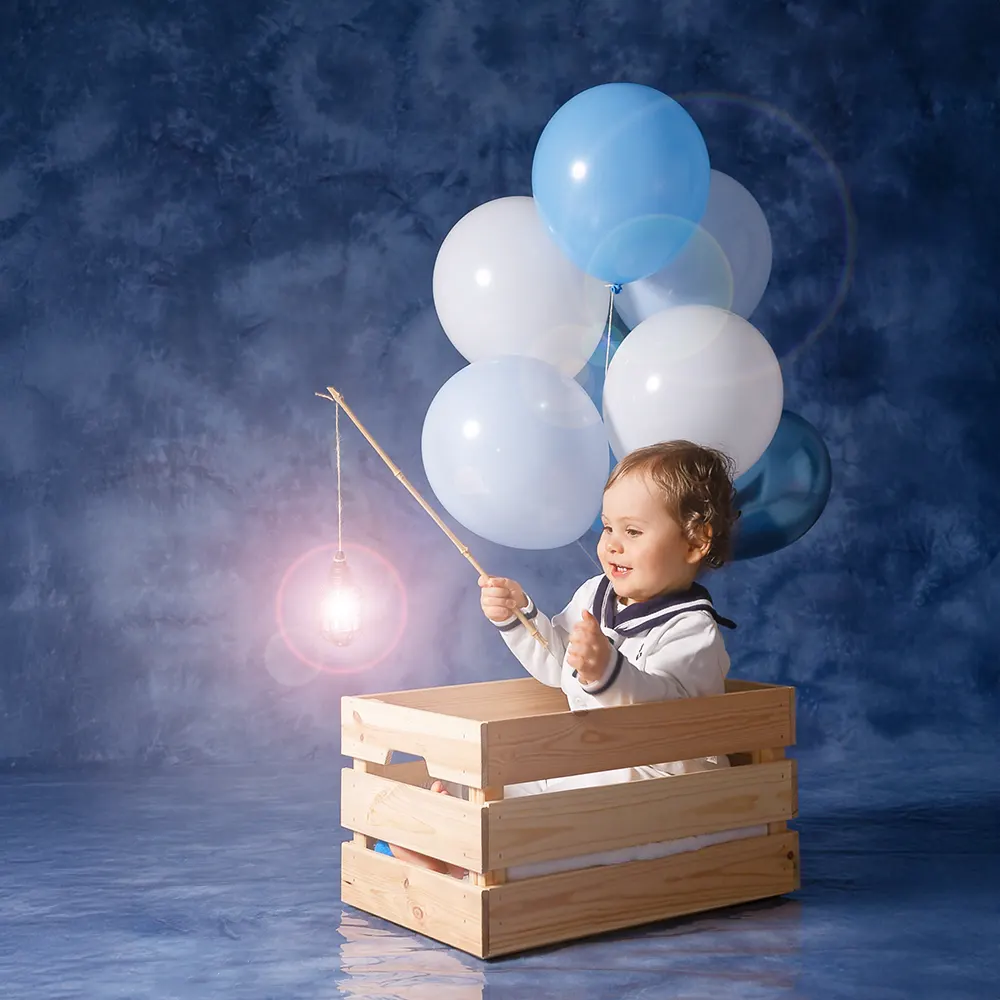 Séance photo d'anniversaire d'un an, bébé matelot dans sa barque en bois, tenant une lumière féerique.