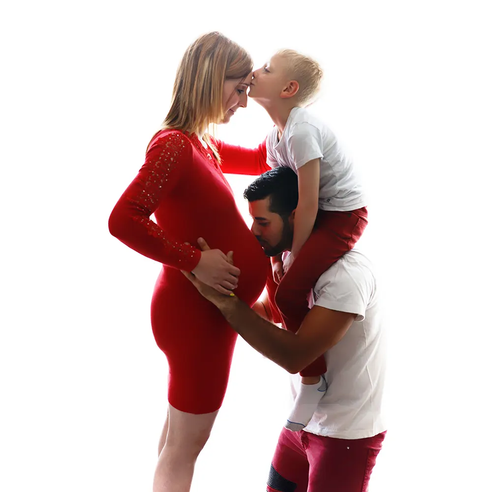 Séance photo de maternité en famille : un couple et leur enfant posant avec tendresse en studio.